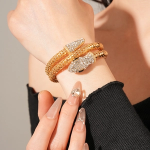 Macro shot of gold snake-shaped bangle with white rhinestones and textured scales