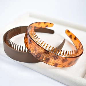 Detail of amber and brown non-slip headbands with teeth on a beige velvet display tray
