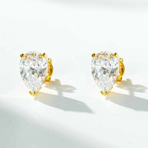Macro shot of elegant pear-shaped white zircon earrings with a golden three-claw setting
