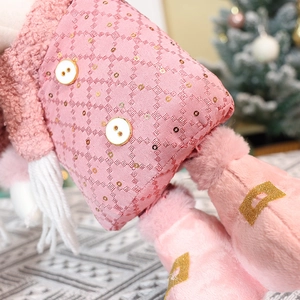 Detailed close-up of pink plush Christmas doll featuring sequined fabric and gold accents