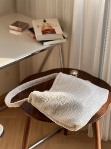 Détail de la texture tissée en tweed crème et de la large bandoulière du sac à main