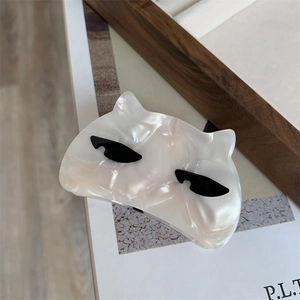 Detail of pearl white acetate cat hair claw clip with black sunglasses pattern decoration