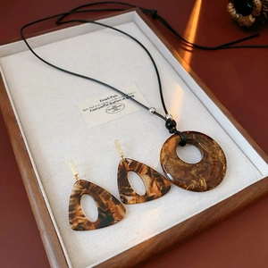 Detail view of retro resin jewelry set featuring leopard print necklace and triangle earrings