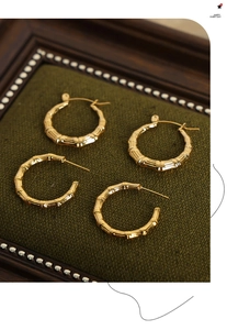 Macro detail of gold-plated bamboo joint hoop earrings on green velvet jewelry box