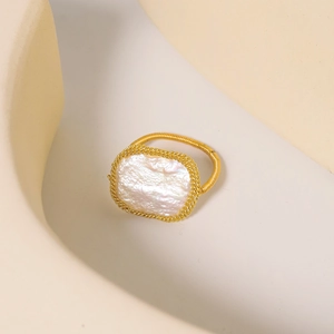 Anello dorato artigianale con perla barocca bianca naturale su sfondo beige elegante
