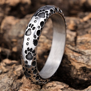 Punk style silver stainless steel ring featuring embossed paw prints on a wooden surface