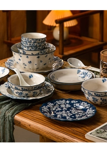 Detail of blue and white floral ceramic tableware set on a rustic wooden table