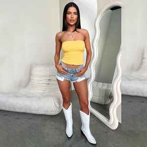 Street style outfit with yellow tube top, denim shorts, and white embroidered boots
