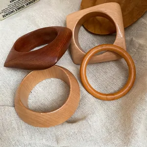 Lot de quatre bracelets en bois minimalistes avec grain naturel sur lin beige clair