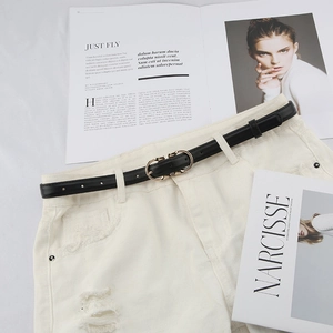 Detail of slim black leather belt with golden horsebit buckle on white denim shorts