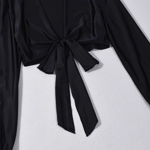 Close-up of black long sleeve crop top with lace-up front detail and silky fabric texture