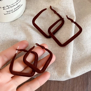 Gros plan de boucles d'oreilles carrées marron foncé avec une texture veloutée floquée