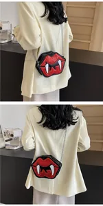 Detail of red sequined vampire lips crossbody bag with white tusks on model in cafe