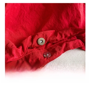 Macro shot of silver magnetic buckle and durable red nylon fabric on a casual tote bag
