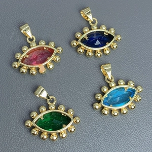 Gold plated evil eye pendants with colorful zircon crystals on a textured background
