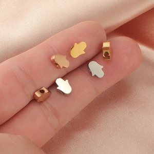 Macro view of five mini metal Hamsa Hand beads in gold, silver, and rose gold finishes