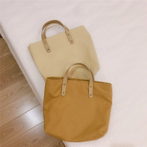 Close-up of minimalist canvas tote bags with faux leather handles and rivet details