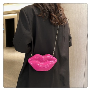 Lip-shaped crossbody bag in bright fuchsia patent leather with gold chain strap detail