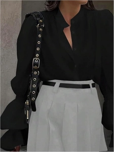 Detail of ruffle sleeve shirt paired with grey pleated skirt and black chain belt