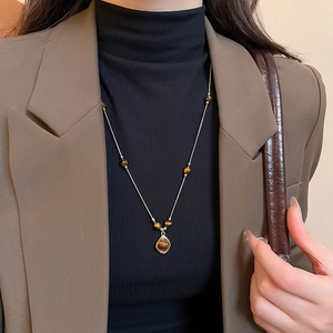 Detailed close-up of a vintage flower tiger eye stone pendant necklace on a model