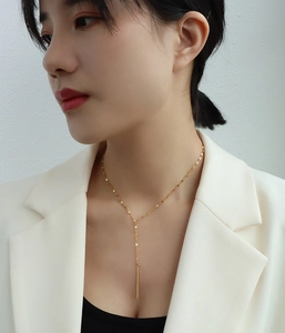 Détail d'un collier en Y doré avec pendentif à pampille porté au cou d'un mannequin