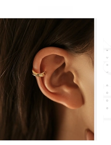 Close-up of golden double-hoop ear cuff with polished liquid metal finish on ear
