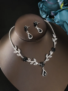 Detailed macro view of five-petal black flower necklace and sparkling drop earrings