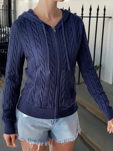 Close-up of navy blue cable knit hoodie featuring a metallic zipper and ribbed cuffs