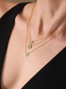 Three-layer gold necklace with diamond-encrusted clover pendants on a female model
