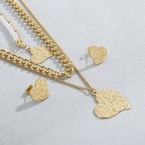 Golden heart jewelry set with layered pearl and metal necklaces and matching stud earrings