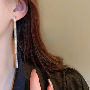 Macro detail of long silver tassel earrings with sparkling crystals on a side-view model