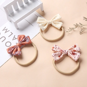 Three floral bow headbands on a white mini bench with warm decorative accents
