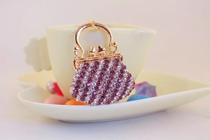 Detail of purple and white rhinestone bag charm on a beige heart-shaped ceramic set
