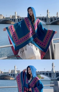 Détail d'un poncho ethnique bleu à capuche avec motifs de cœurs roses et franges