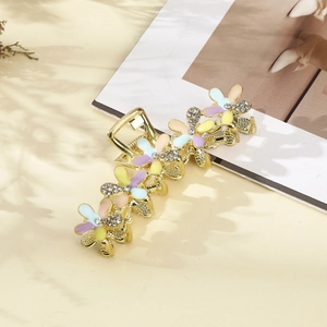 Detailed view of golden hair claw clip with colorful enamel flowers and crystals