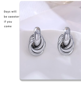 Detailed view of silver multi-loop twisted stud earrings on a white ceramic plate