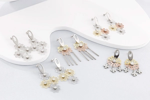 Détail de cinq paires de boucles d'oreilles fleurs ajourées et strass en or et argent