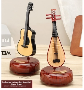 Close-up of miniature vintage guitar and pipa music boxes on wood bases with retro details