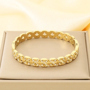 Detailed view of gold hollow-out stainless steel bangle with inlaid crystals on silk