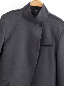Détail d'un blazer gris foncé avec col montant et fermeture diagonale à bouton unique