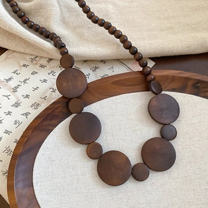Detail of vintage wooden beaded necklace with geometric circles on a rustic fabric background