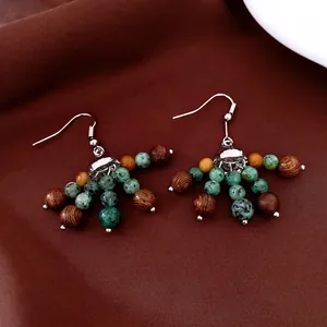 Boucles d'oreilles ethniques avec perles de pierre verte et bois sur fond de soie