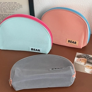 Detailed view of three mesh toiletry bags in mint green, peach pink and light grey