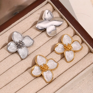 Macro shot of gold and silver flower earrings with white enamel in a wooden jewelry box