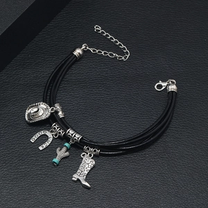 Detailed close-up of lucky charms on black leather bracelet with cowboy hat and horseshoe