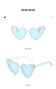 Detail view of blue heart-shaped sunglasses with elegant white pearl frame decorations
