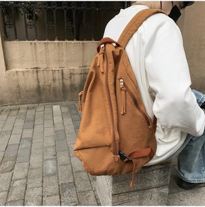 Detailed outdoor view of brown canvas sling bag with multi-zipper design for casual style