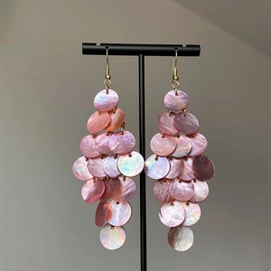 Pink iridescent shell tassel earrings with bohemian tiered dangle design on display