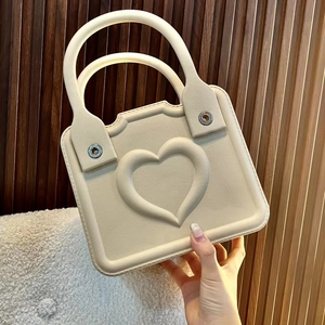 Detail showing creamy EVA beach tote with embossed heart pattern and metallic rivets