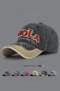 Detail of embroidered HOLA logo on washed cotton vintage baseball cap with worn edges